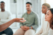 © KayExam/peopleimages.com - Talking, hands and group of people in therapy for mental health support, sharing story or recovery. Counseling, listen or rehabilitation for trauma, addiction and meeting for wellness, advice or help