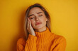 © kongkiat chairat - A young woman in an orange sweater expressing distress with a hand on her head against a vibrant yellow background.