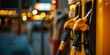 © StockUp - Close-up of yellow fuel nozzles at a gas station, highlighting the metal and rubber textures with a bokeh effect.