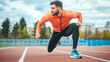 © Galib - A man in a bright orange sweatshirt and black shorts gets ready to run on an outdoor track.