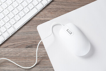 Wall Mural - Computer mouse with mousepad and keyboard on wooden desk, top view