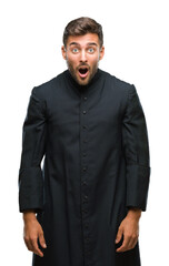 Wall Mural - Young catholic christian priest man over isolated background afraid and shocked with surprise expression, fear and excited face.