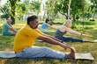 © pressmaster - Side view of mature multiethnic man in yellow t-shirt and grey sweatpants touching toes by fingertips while exercising on mat