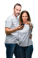 Wall Mural - middle age hispanic couple texting message on smartphone ver isolated background pointing with finge