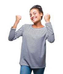 Young braided hair african american girl wearing sweater over isolated background very happy and excited doing winner gesture with arms raised, smiling and screaming for success. Celebration concept.