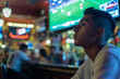 © AI_images_for_people - A young Hispanic sports fan, intensely watching a match on a large TV in a lively bar. The background features a crowded bar area with other patrons, sports memorabilia, and vibrant lighting.