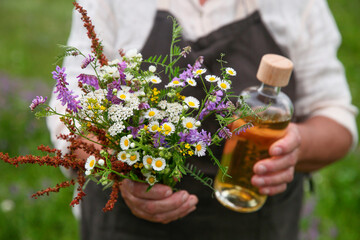 Senior woman with tincture and wildflowers outdoors, closeup