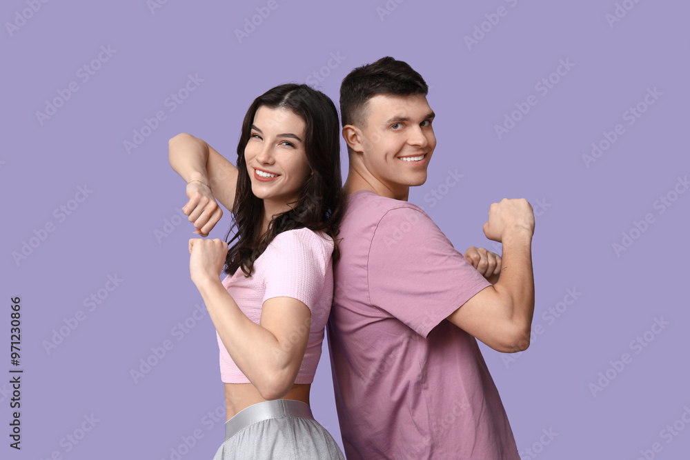 Happy young couple dancing on lilac background