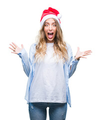 Beautiful young blonde woman wearing christmas hat over isolated background celebrating crazy and amazed for success with arms raised and open eyes screaming excited. Winner concept