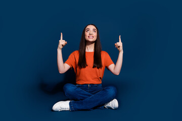 Wall Mural - Photo of lovely adorable woman wear stylish clothes sit floor introduce empty space isolated on dark blue color background