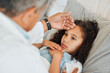 © peopleimages.com - Healthcare, doctor and child with fever, bed and touch on forehead for temperature, cold and house. Sick, girl and help of medical professional in home, patient and infection of flu, kid and hand