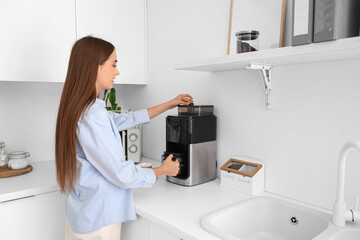 Poster - Beautiful young happy woman making coffee with machine at kitchen in office