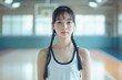 © Joaquin Corbalan - A young Chinese girl with black braided hair stands confidently in a gym, ready for basketball practice in the afternoon