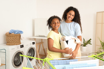 Wall Mural - African-American woman and her daughter with laundry at home