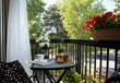 © mutter - During summer, the terrace of a small apartment is bright and filled with flowers and a coffee table