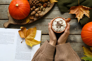 Poster - Female hands with cup of cocoa, book and tray on wooden background