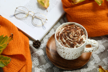 Autumn composition with cup of cocoa and scarf on plaid as background, closeup