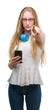 © Krakenimages.com - Blonde teenager woman holding smartphone and wearing headphones pointing with finger to the camera and to you, hand sign, positive and confident gesture from the front