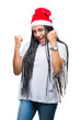 © Krakenimages.com - Young braided hair african american girl wearing christmas hat over isolated background very happy and excited doing winner gesture with arms raised, smiling and screaming for success.