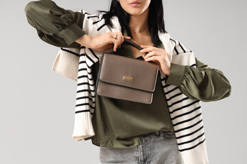 Beautiful young woman with stylish bag on grey background, closeup