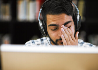 Poster - Man, university student and tired on computer with headphones in library for internet, online error and research. Male person, exhausted and burnout or headache with assignment deadline and study