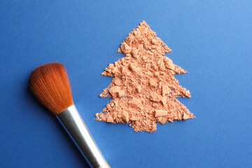 Wall Mural - Christmas tree made with face powder and brush on blue background, top view