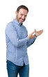 © Krakenimages.com - Handsome middle age elegant senior man over isolated background Inviting to enter smiling natural with open hand