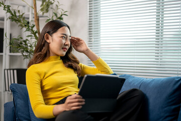 Wall Mural - young businesswoman having headache while working from home using tablet computer