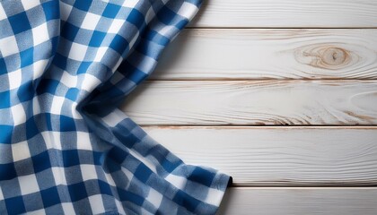 Blue checkered tablecloth textile on white wooden table background
