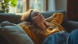 © vefimov - A woman is laying on a couch with her head on a pillow. She is wearing a yellow sweater and blue jeans. Scene is relaxed and comfortable