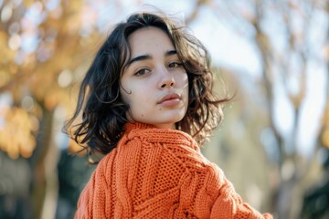 Poster - A woman wearing an orange sweater is standing in a park. She has a serious expression on her face