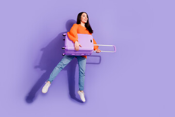 Poster - Photo of lovely positive glad girl wear trendy orange clothes hold bag look empty space isolated on violet color background