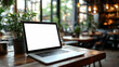 © Siasart - A laptop on a wooden table in a cozy caf? with greenery in the background.