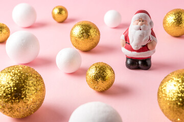 Wall Mural - Gold and white glitter ball decoration with small Santa Claus on pink background. New Year minimal concept.