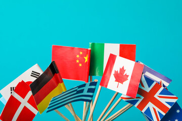 Wall Mural - Small paper flags of different countries on light blue background