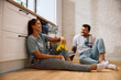 © Drazen - Young happy couple relaxing on floor after washing dishes in  kitchen.