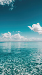 Calm turquoise ocean under clear blue sky with scattered clouds