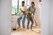 © Drazen - Carefree couple singing and dancing while cleaning their home.