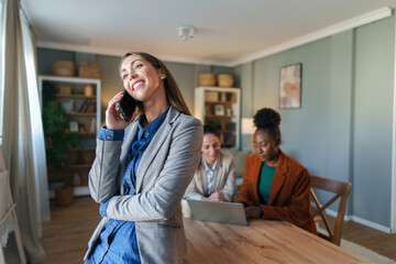 Wall Mural - Smiling Businesswoman on Phone with Team in Background