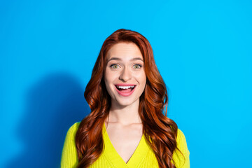 Wall Mural - Photo of impressed funny girl with ginger hairstyle dressed yellow knit cardigan astonished staring isolated on blue color background