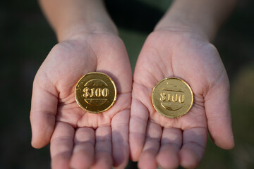 Children's palms with chocolate coins. Fake money. Children's currency.