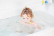 © famveldman - Little baby in bath tub playing with soap foam