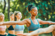 © MVProductions - Group of multiethnic women stretching arms outdoor. Yoga class doing breathing exercise at park. Beautiful fit women doing breath exercise together with outstretched arms