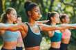 © MVProductions - Group of multiethnic women stretching arms outdoor. Yoga class doing breathing exercise at park. Beautiful fit women doing breath exercise together with outstretched arms