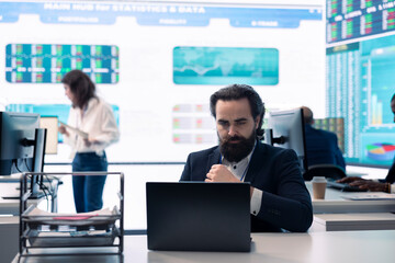 General director examining statistics big data on computer in a control room, makes a briefing report. Business manager studying sales numbers to adapt within market conditions.