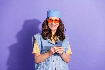 Poster - Photo portrait of pretty retired woman hold device wear trendy denim hipster outfit isolated on violet color background