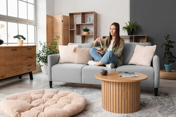 Canvas Print - Young woman with Tibetan singing bowl sitting on sofa at home