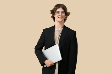 Male programmer in eyeglasses holding modern laptop on beige background
