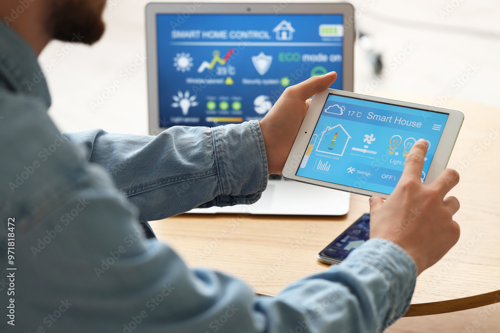 Young man using smart home control panel in room, closeup