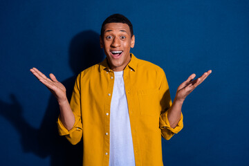 Poster - Photo of young guy wearing yellow shirt shrug shoulders excited dont know staying questioned isolated on dark blue color background